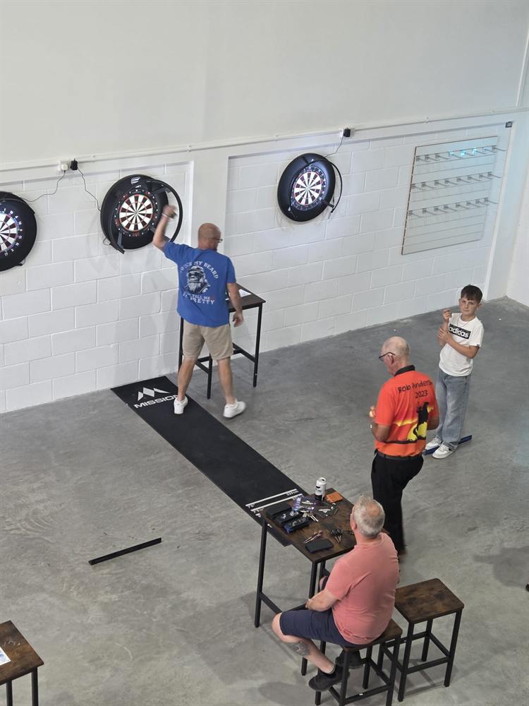 A junior player, a coach and older members throwing together at Wiltshire Darts House in Swindon