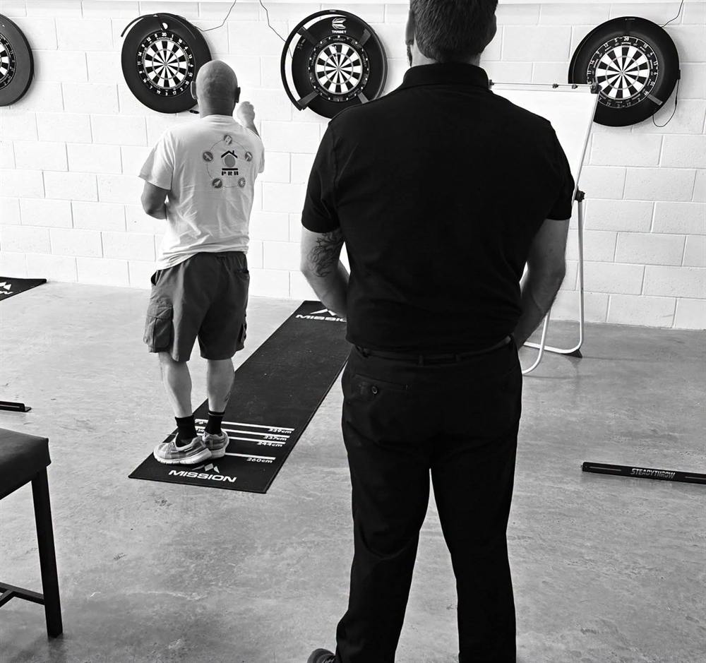 A coach watching a player throw from the oche at Wiltshire Darts House, Swindon